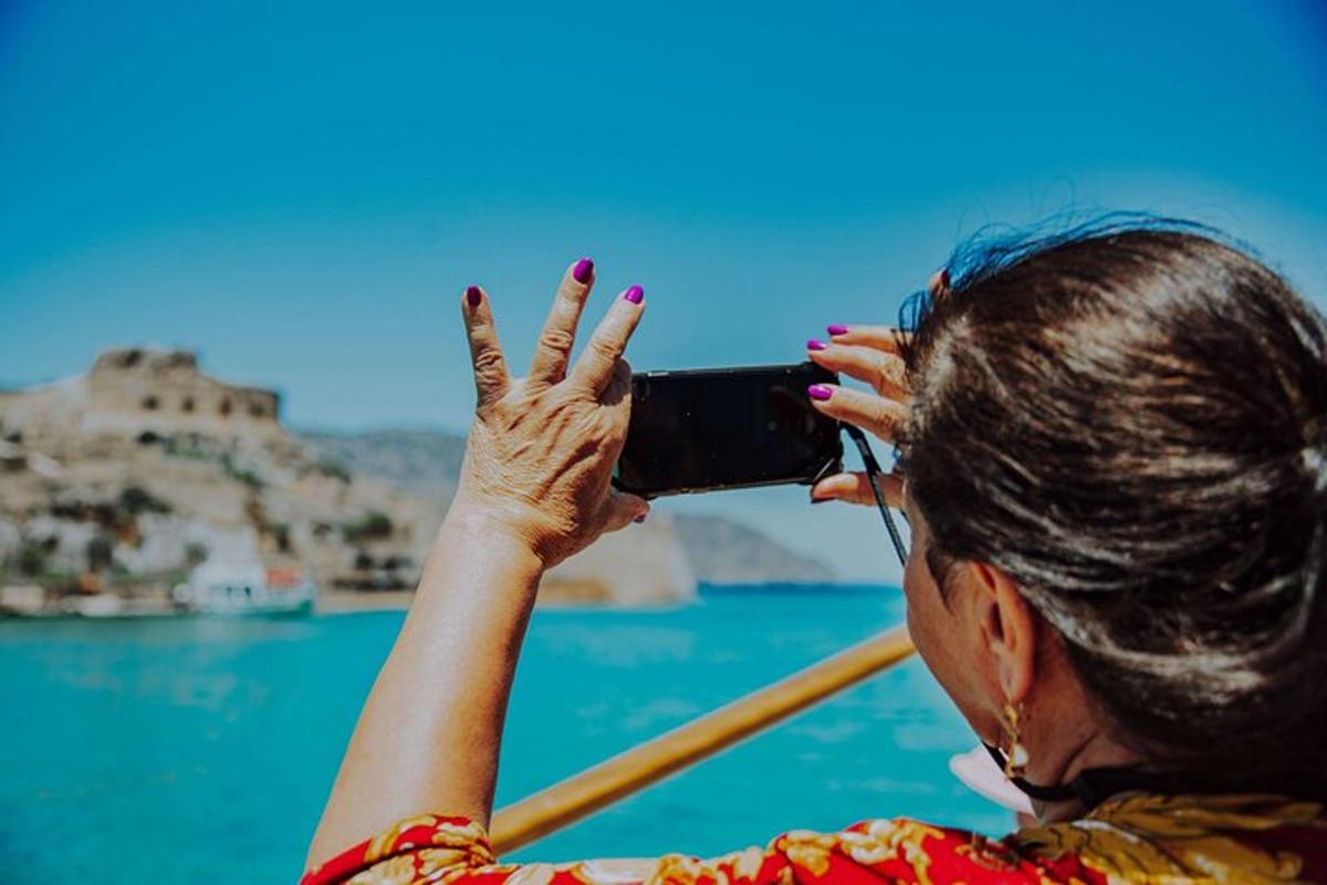 seorang wanita mengambil gambar lautan dengan telefon bimbitnya