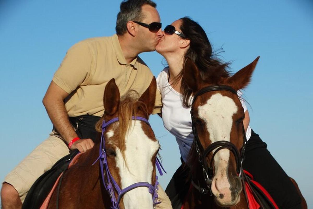 um homem e uma mulher se beijando enquanto cavalgam