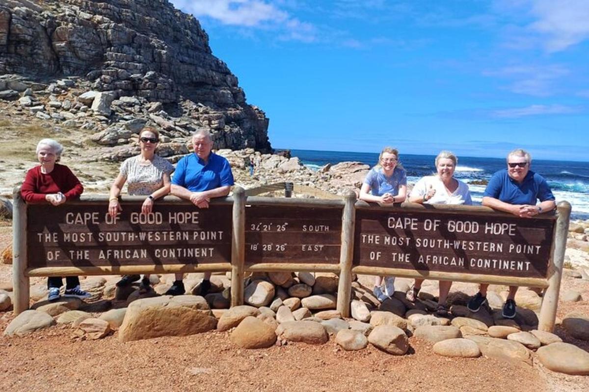 Un grupo de personas sentadas en un cartel en la playa.