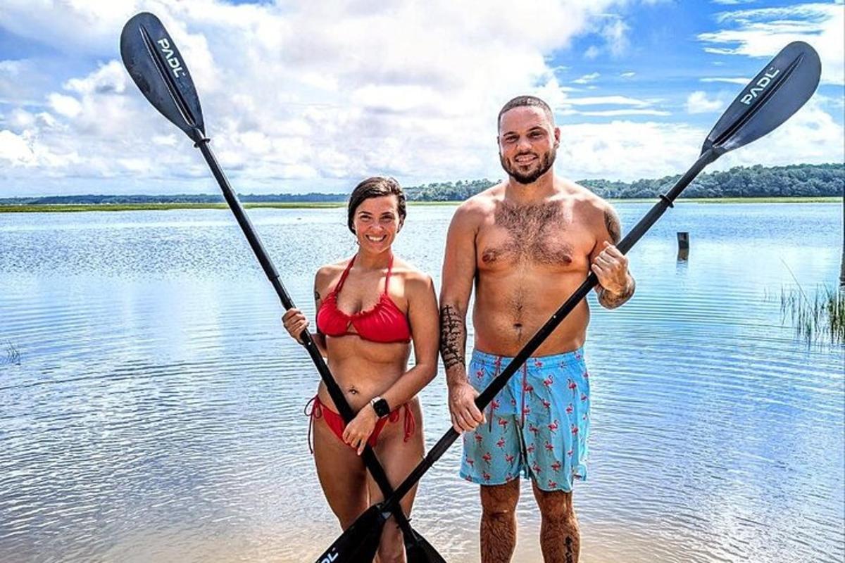 Un hombre y una mujer de pie en el agua con remos.