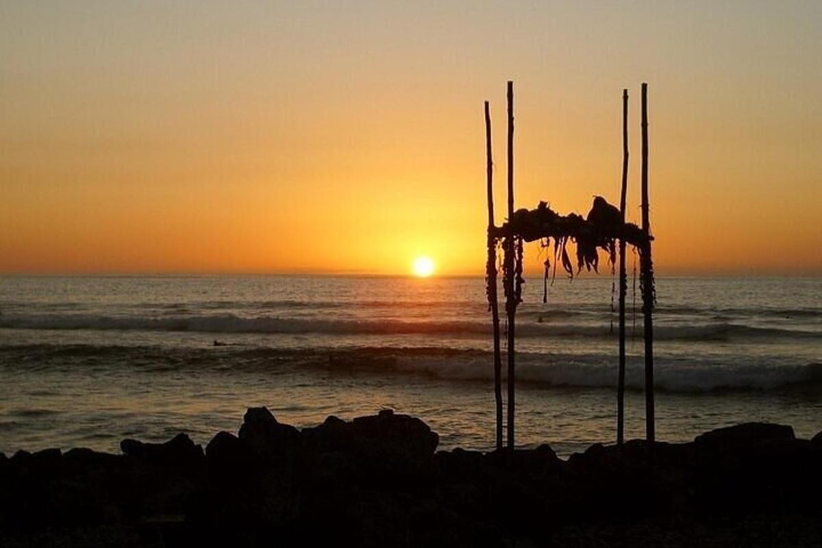 un tramonto sulla spiaggia con l'oceano e una capanna