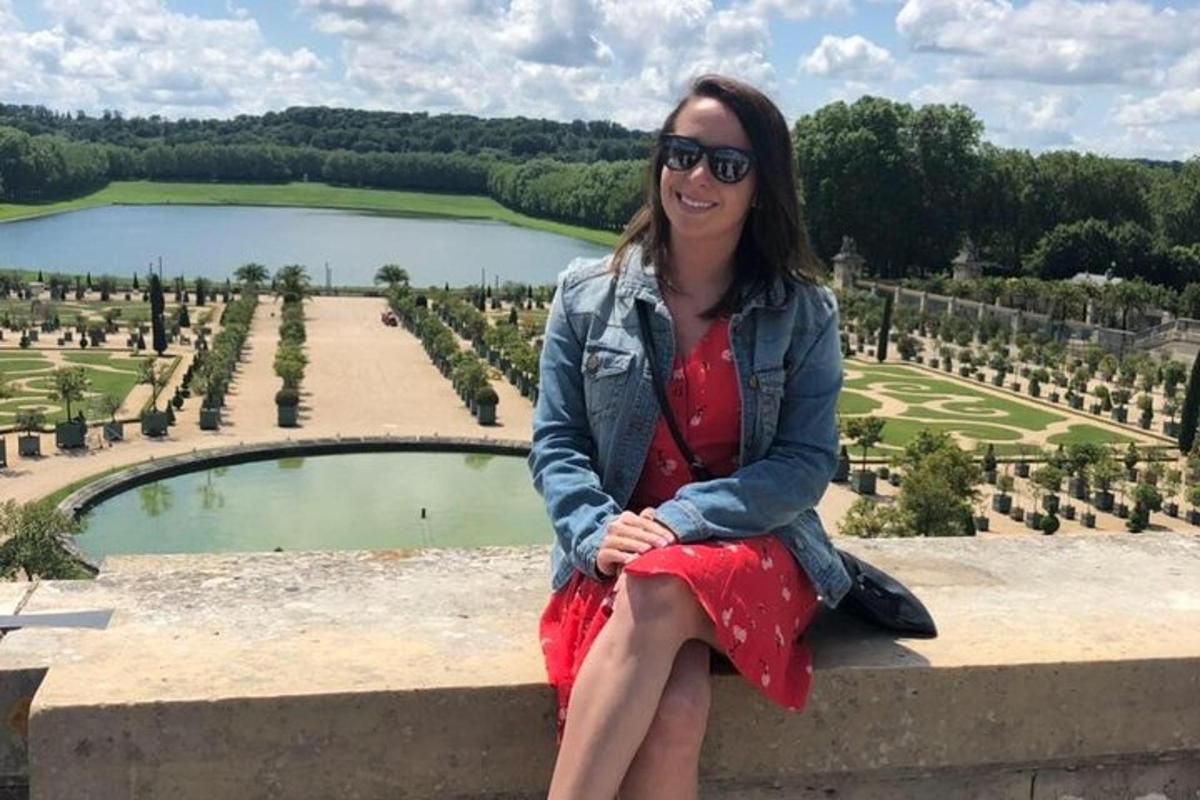 a woman sitting on a wall in front of a lake