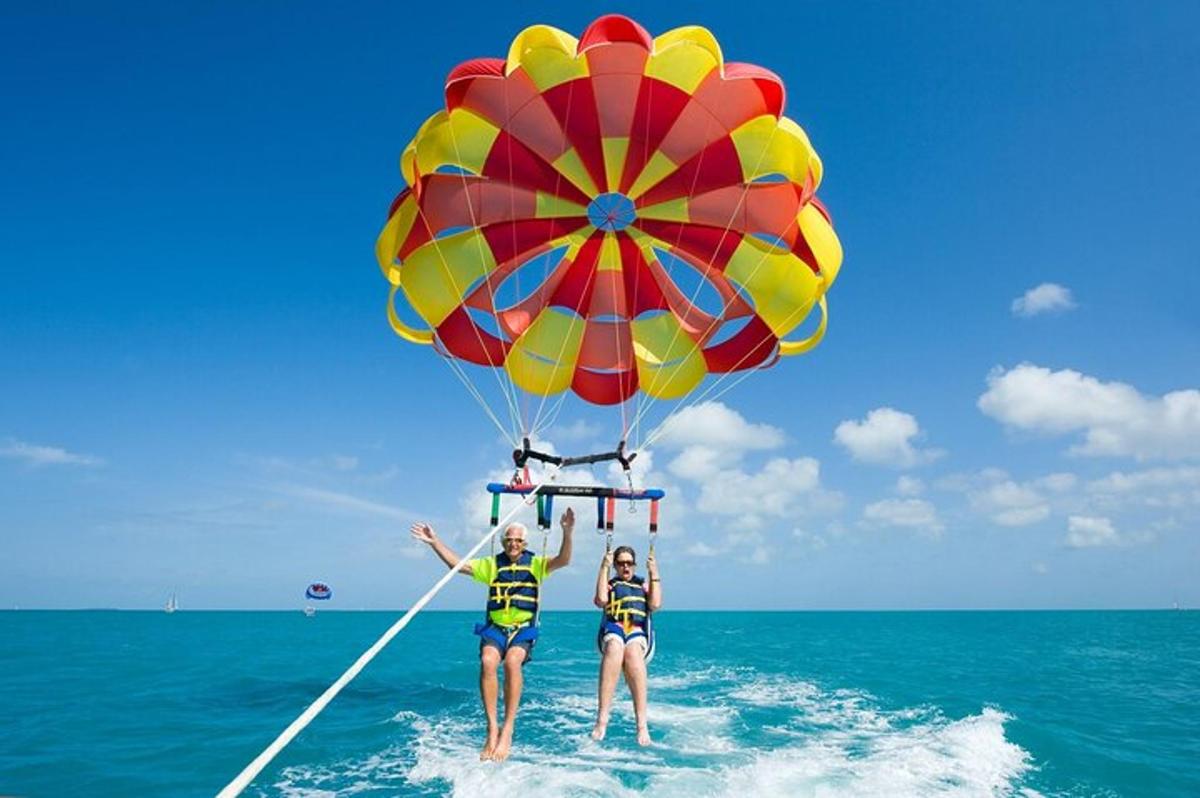 two people are standing in the water with a parachute