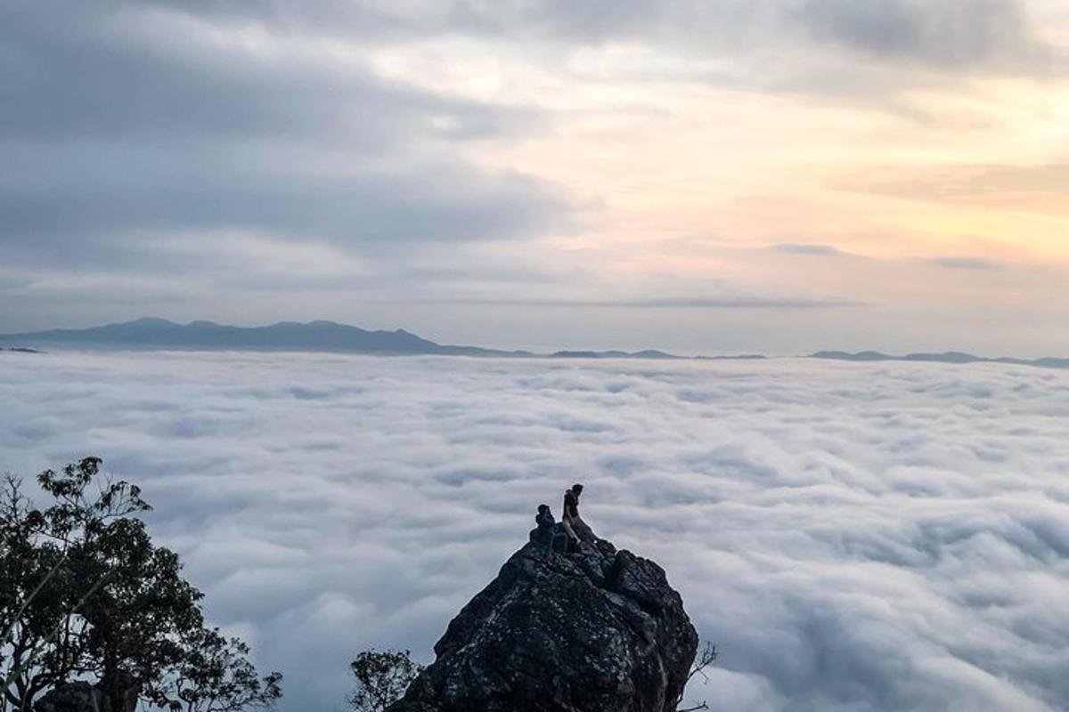 two people standing on top of a mountain above the clouds