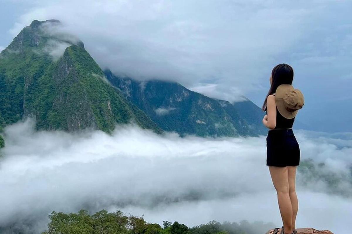 a woman standing on top of a mountain looking at the clouds