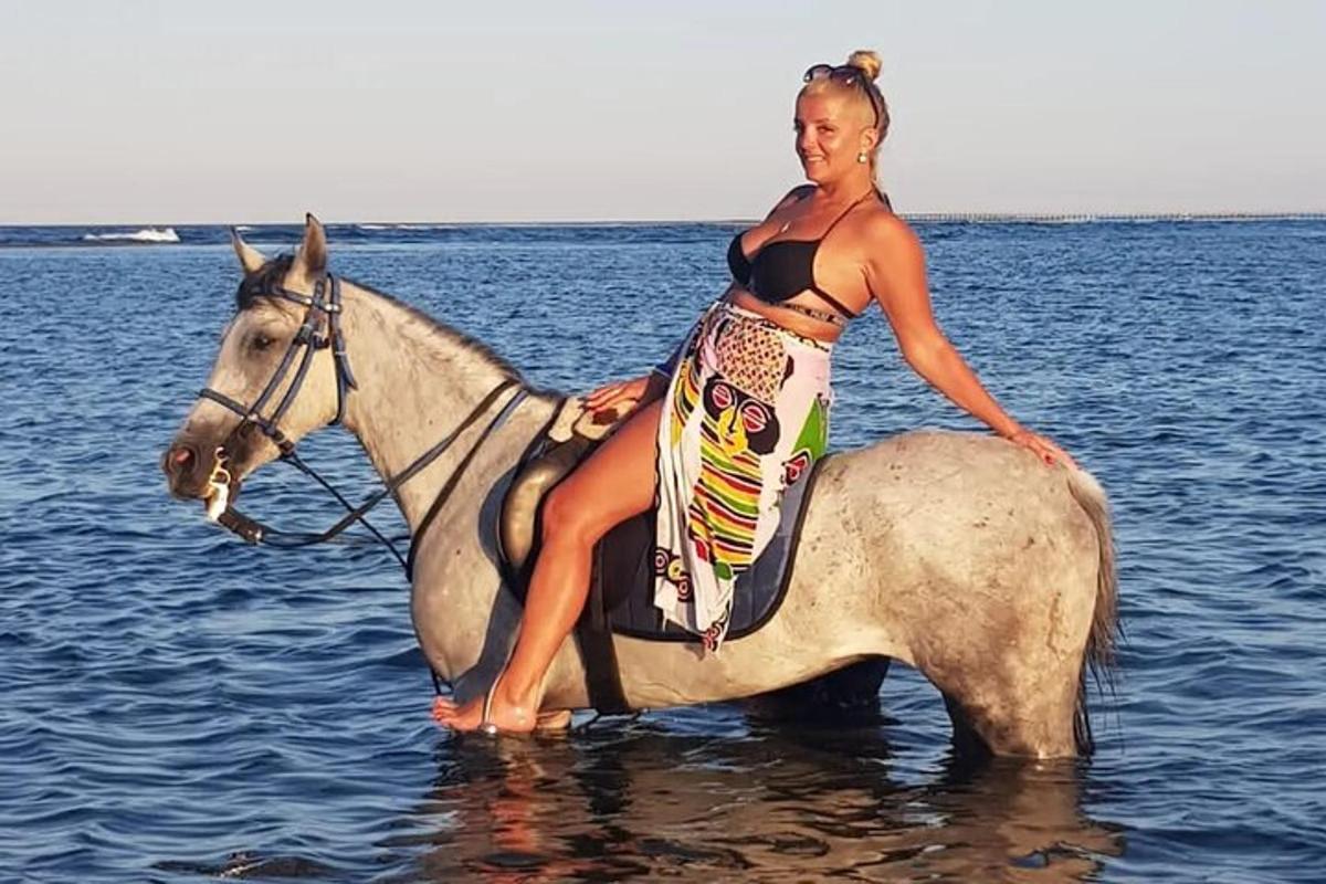 kona situr á hesti í vatninu