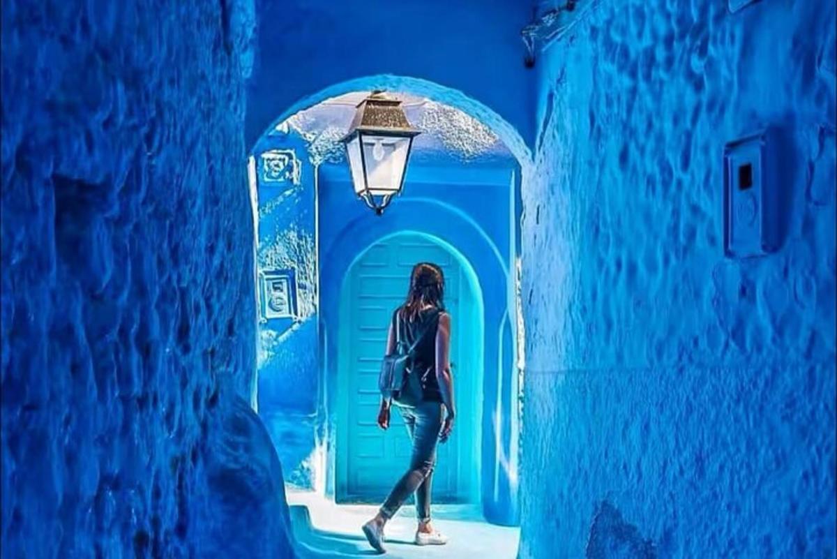 a woman walking through a blue tunnel with a light