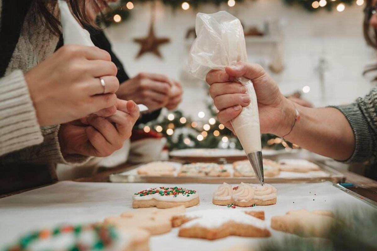 Un grupo de personas haciendo galletas frente a un árbol de Navidad.