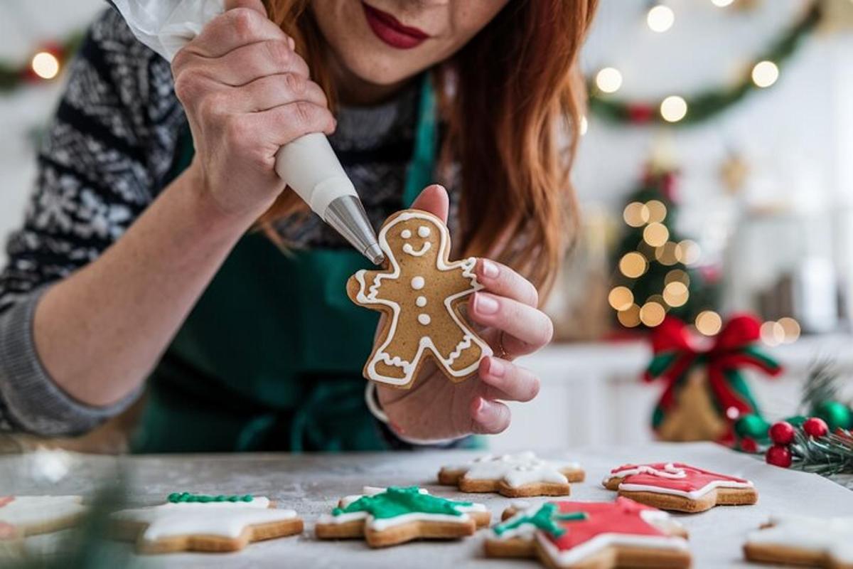 Una mujer sosteniendo un hombre de jengibre frente a galletas navideñas.