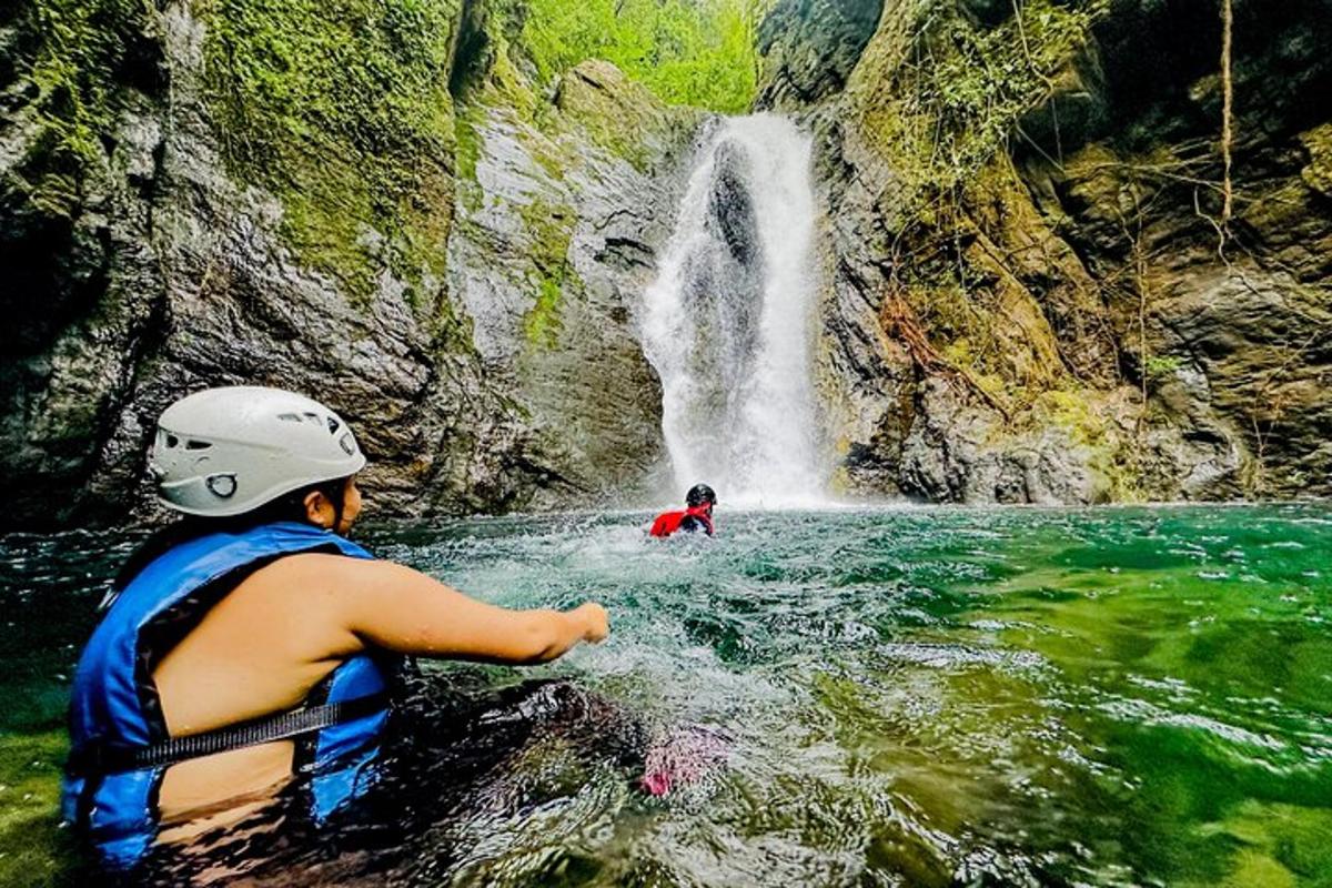 a boy in a life vest in front of a waterfall