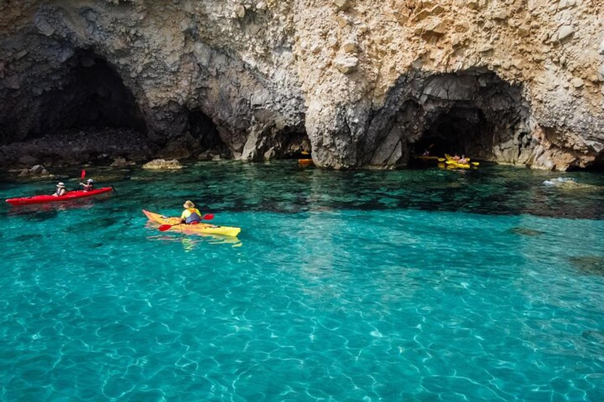 two people in kayaks in the water near a cave
