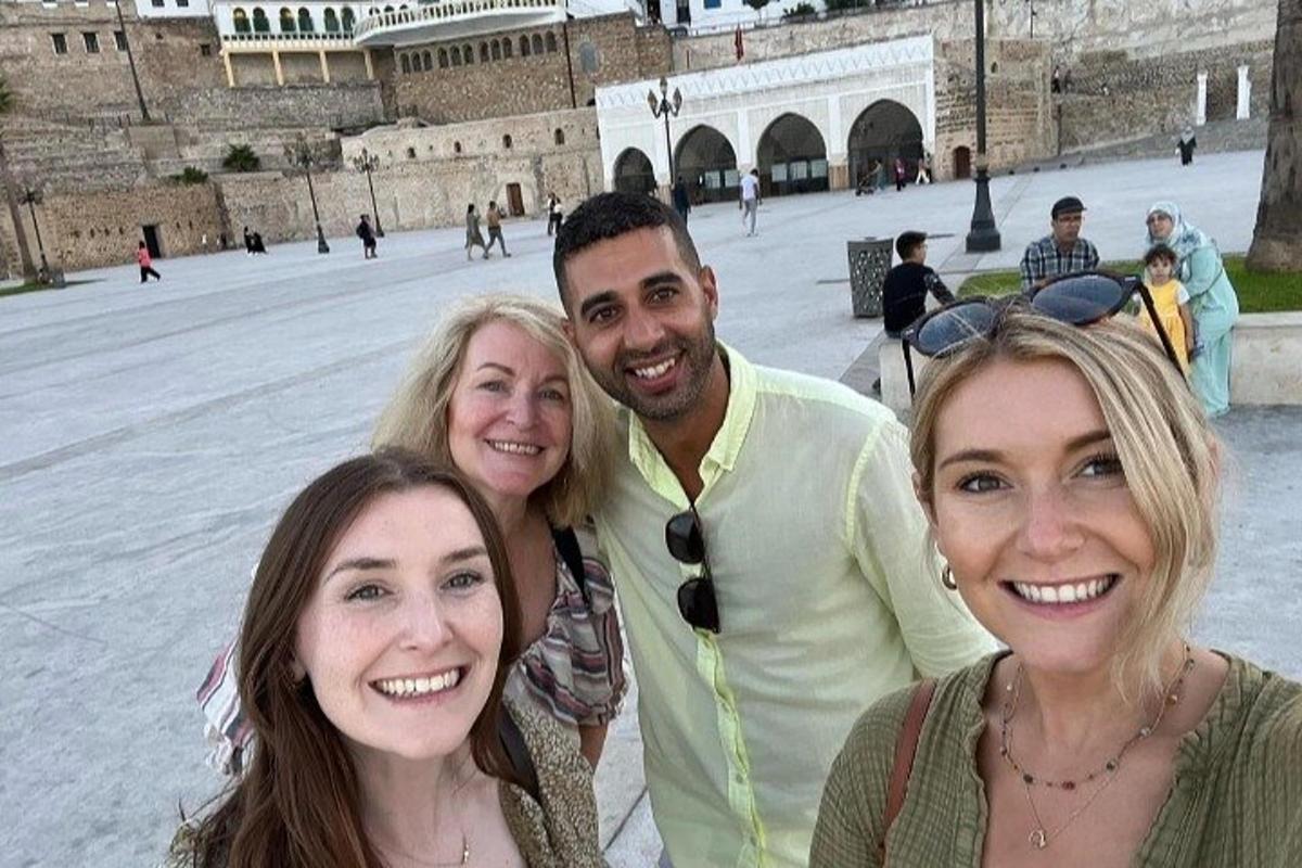 Un hombre y tres mujeres posando para una foto frente a un edificio.