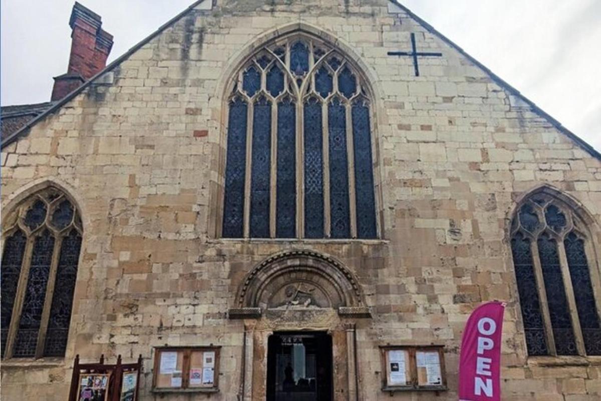 une grande église en pierre avec un panneau rose devant
