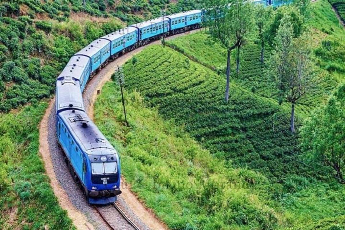 a blue train traveling down the tracks on a hill