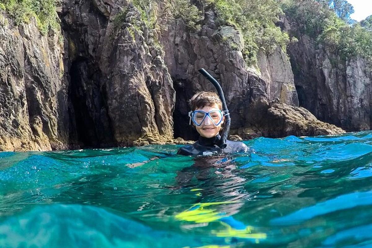 a man in the water in front of a cliff