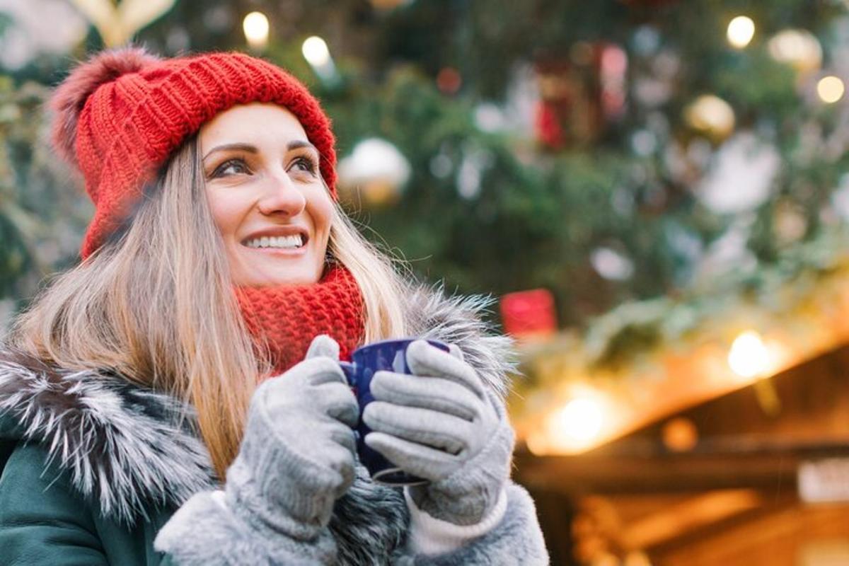 una donna che tiene una tazza di caffè davanti a un albero di Natale