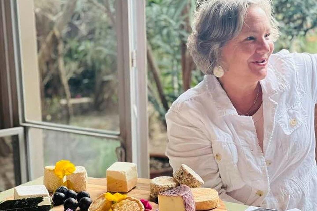 μια γυναίκα που κάθεται σε ένα τραπέζι με ένα σωρό τυριά