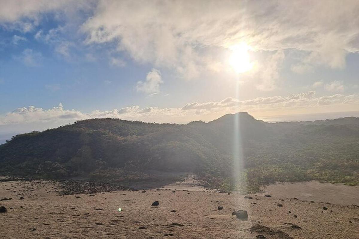 a view of a mountain with the sun in the sky