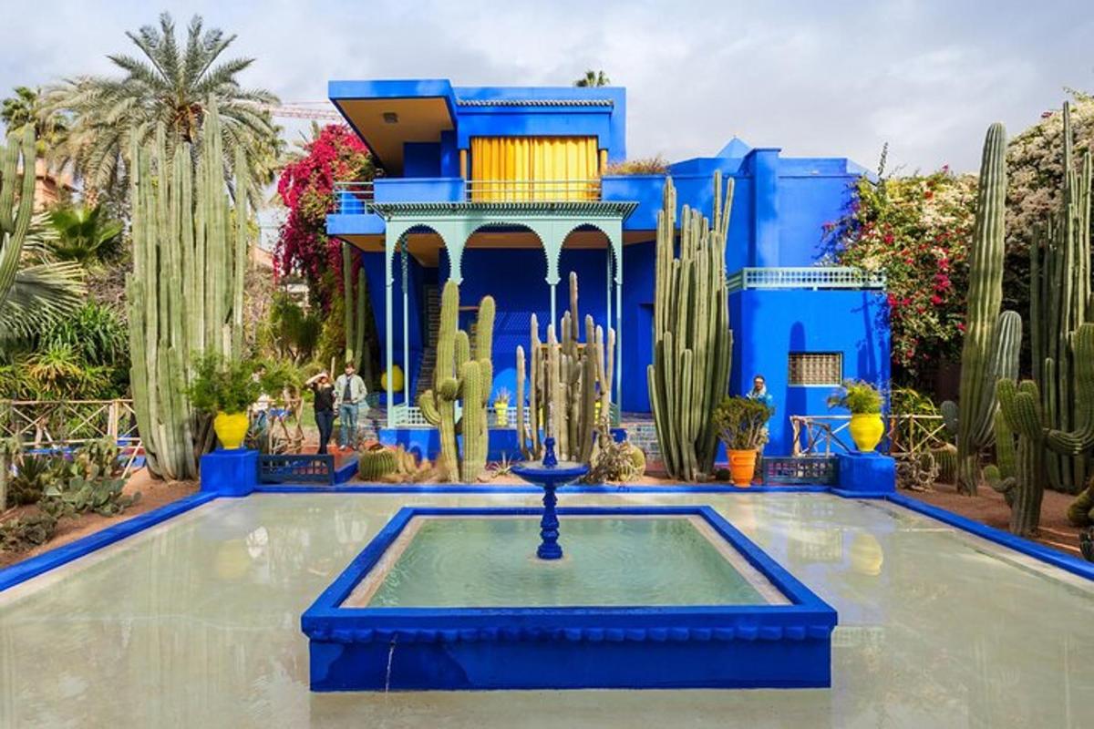 a blue building with a fountain in the middle of a garden
