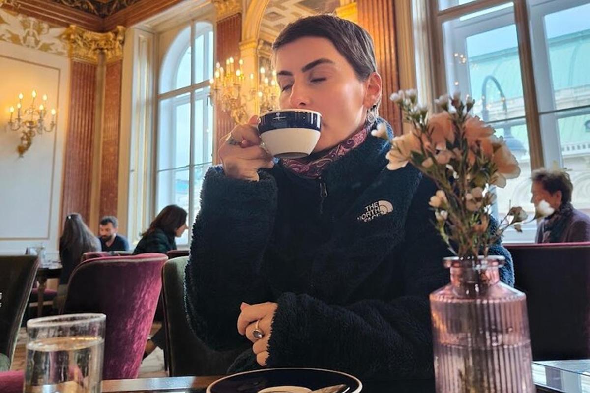 žena sedící u stolu a pije šálek kávy