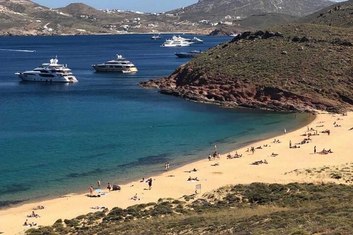 Un grupo de personas en una playa con barcos en el agua.