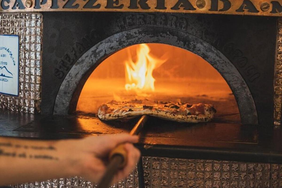 eine Person schiebt eine Pizza in einen Ofen