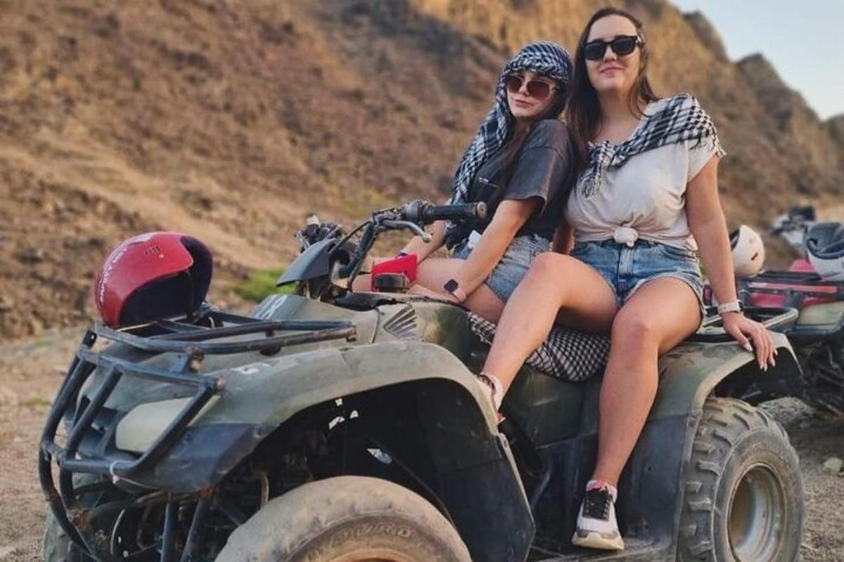 two women sitting on the back of a atv
