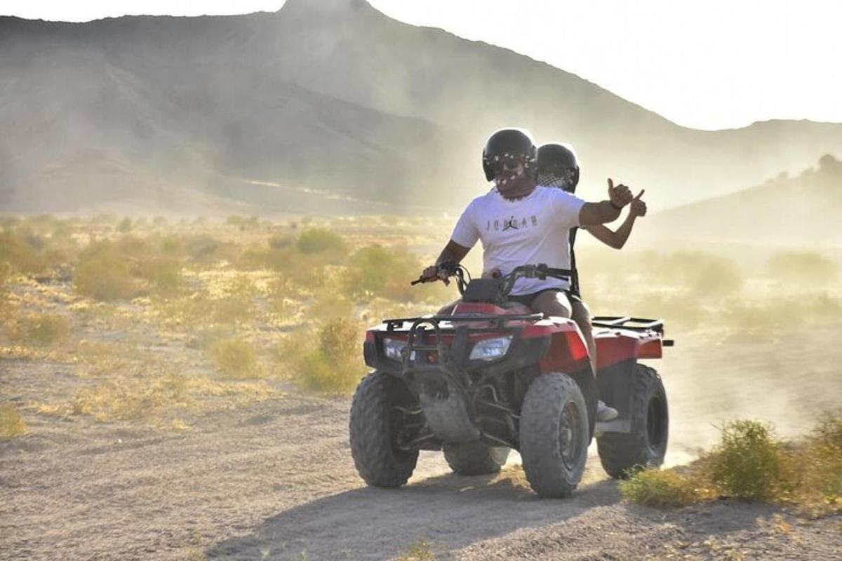 two people riding a quad bike on a dirt road