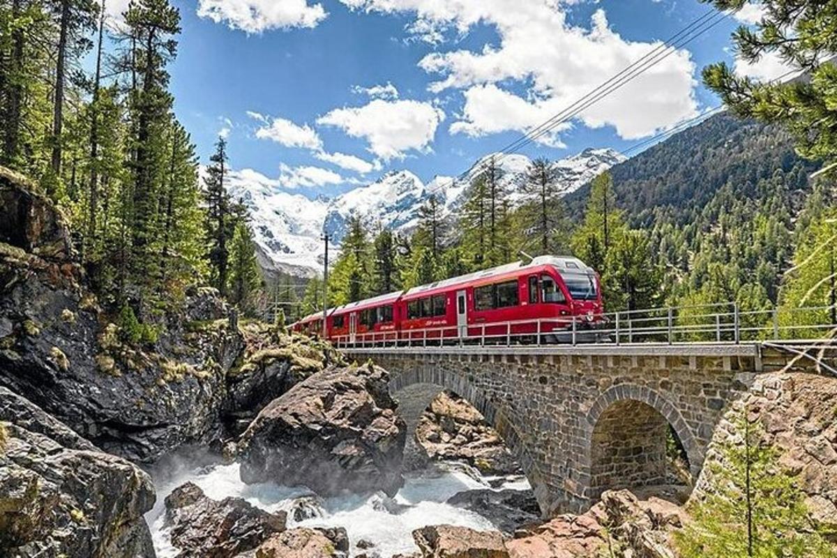 un tren vermell creuant un pont sobre un riu