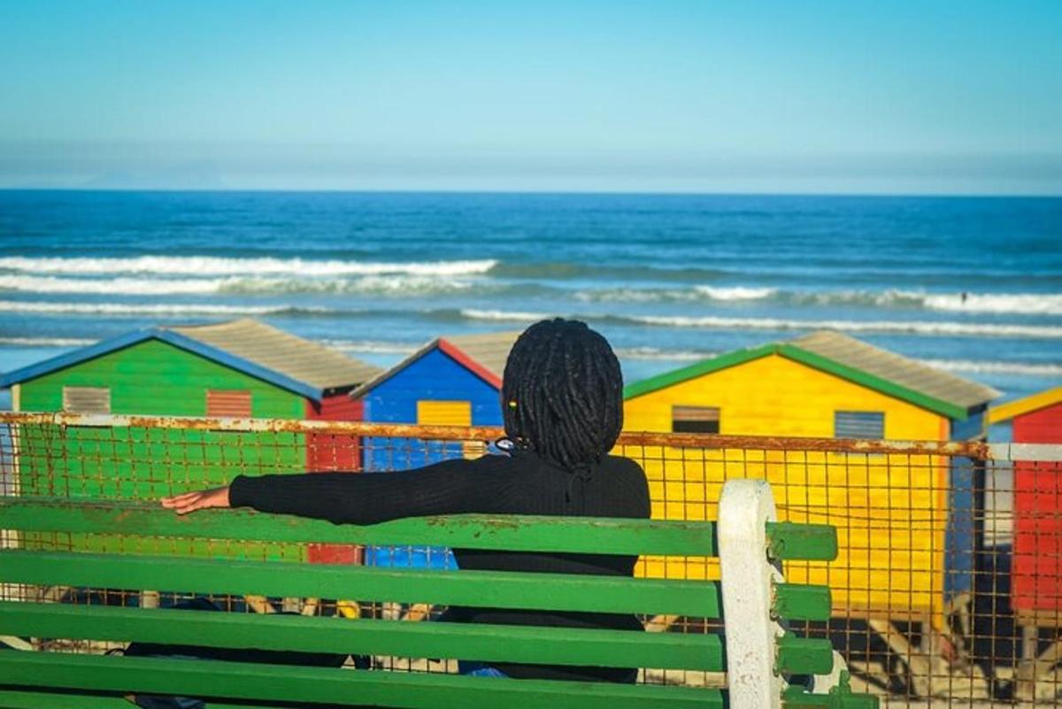 una persona sentada en un banco mirando la playa