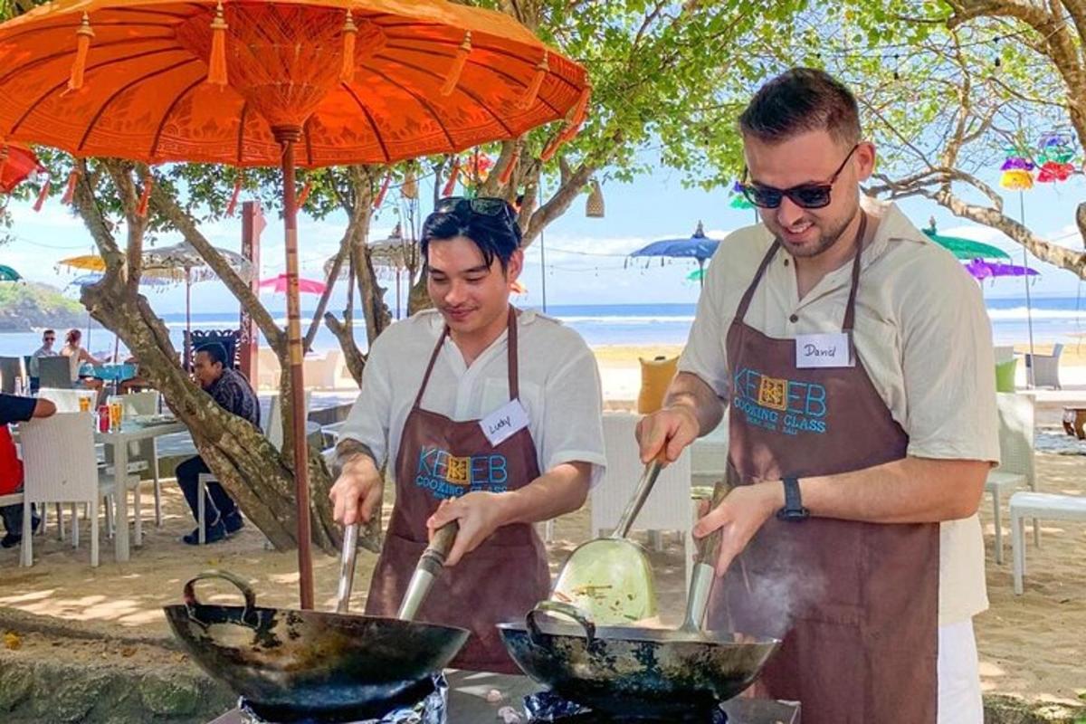 due uomini che cucinano il cibo su una griglia sotto un ombrello