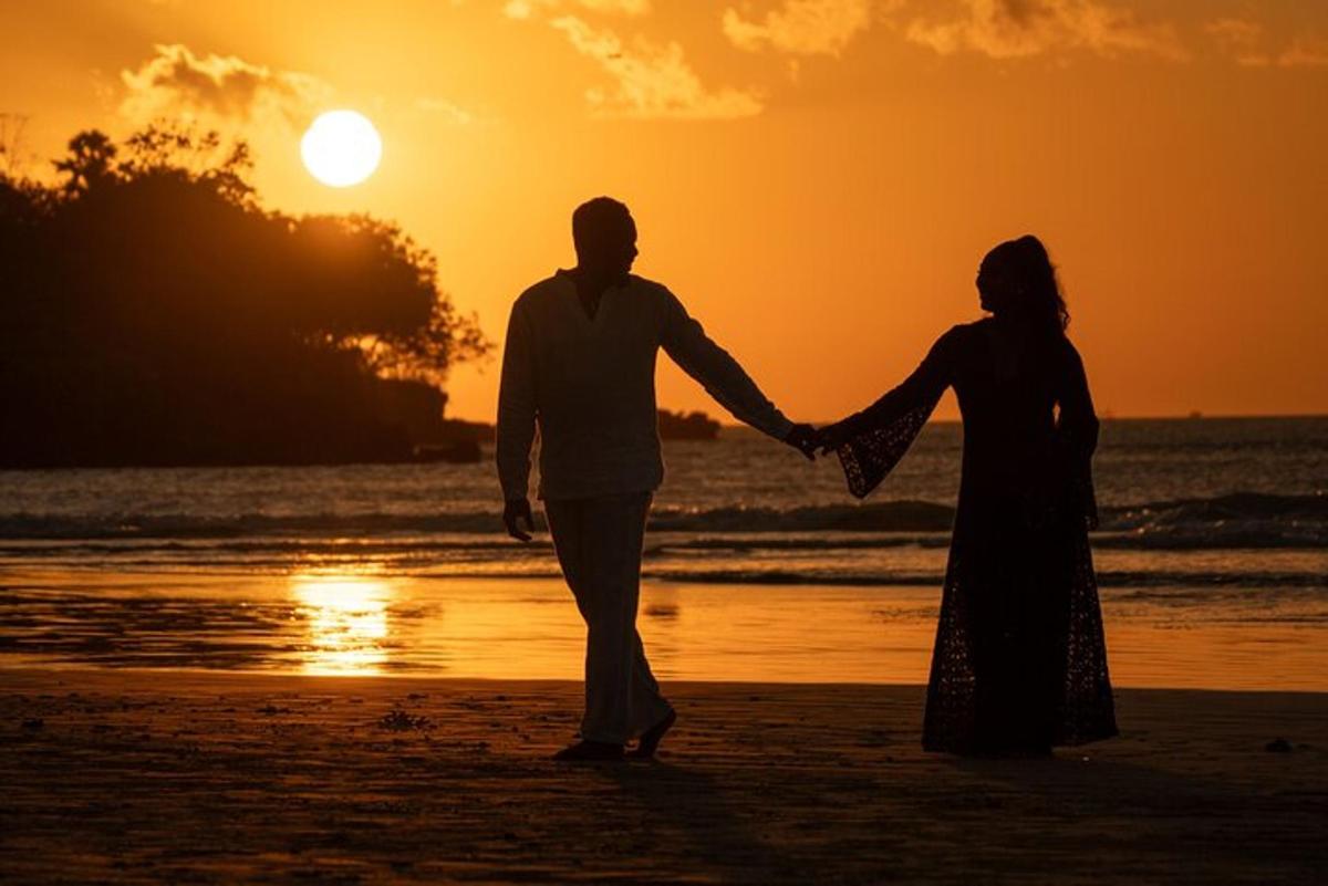 a man and woman walking on the beach at sunset