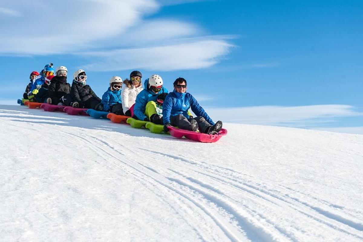 a group of people riding on a sled down a snow covered slope