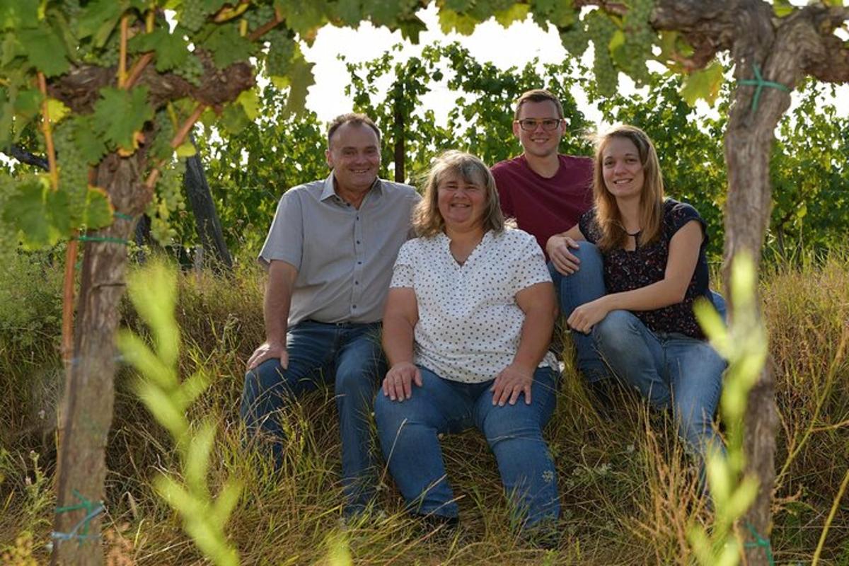 a family sitting in the grass under a tree