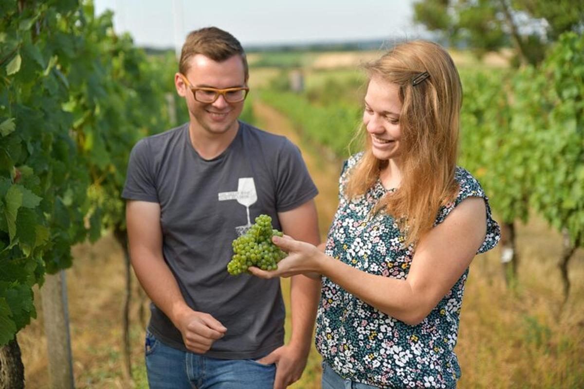 a man and a woman holding a bunch of grapes