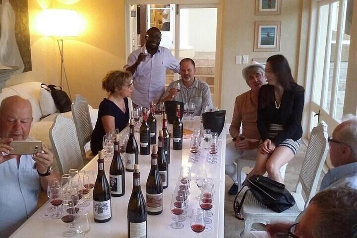 skupina ljudi, ki sedijo okoli mize s steklenicami vina