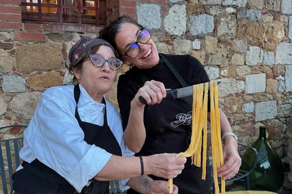 a woman standing next to a woman holding noodles