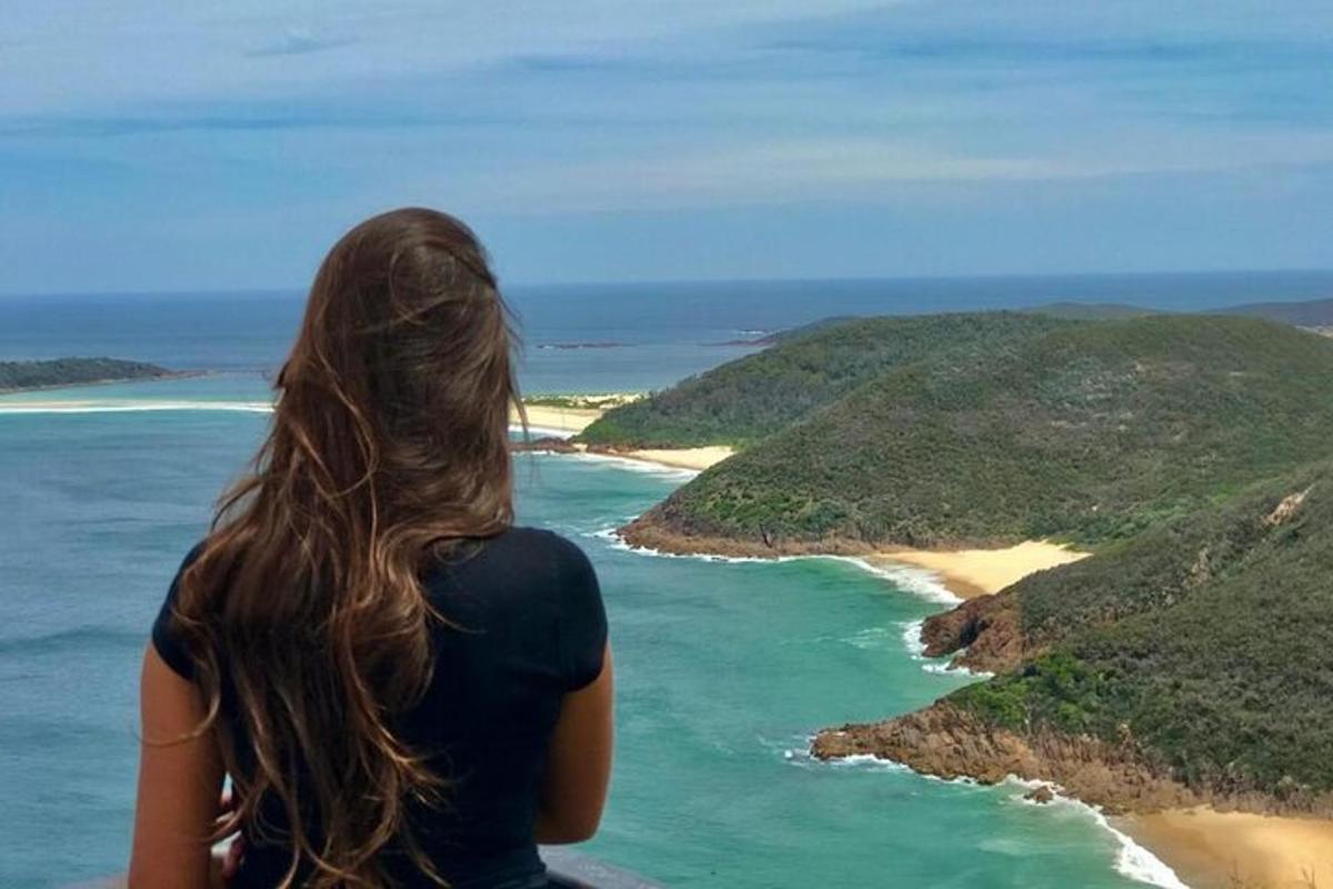ženska, ki stoji na pečini in gleda na ocean