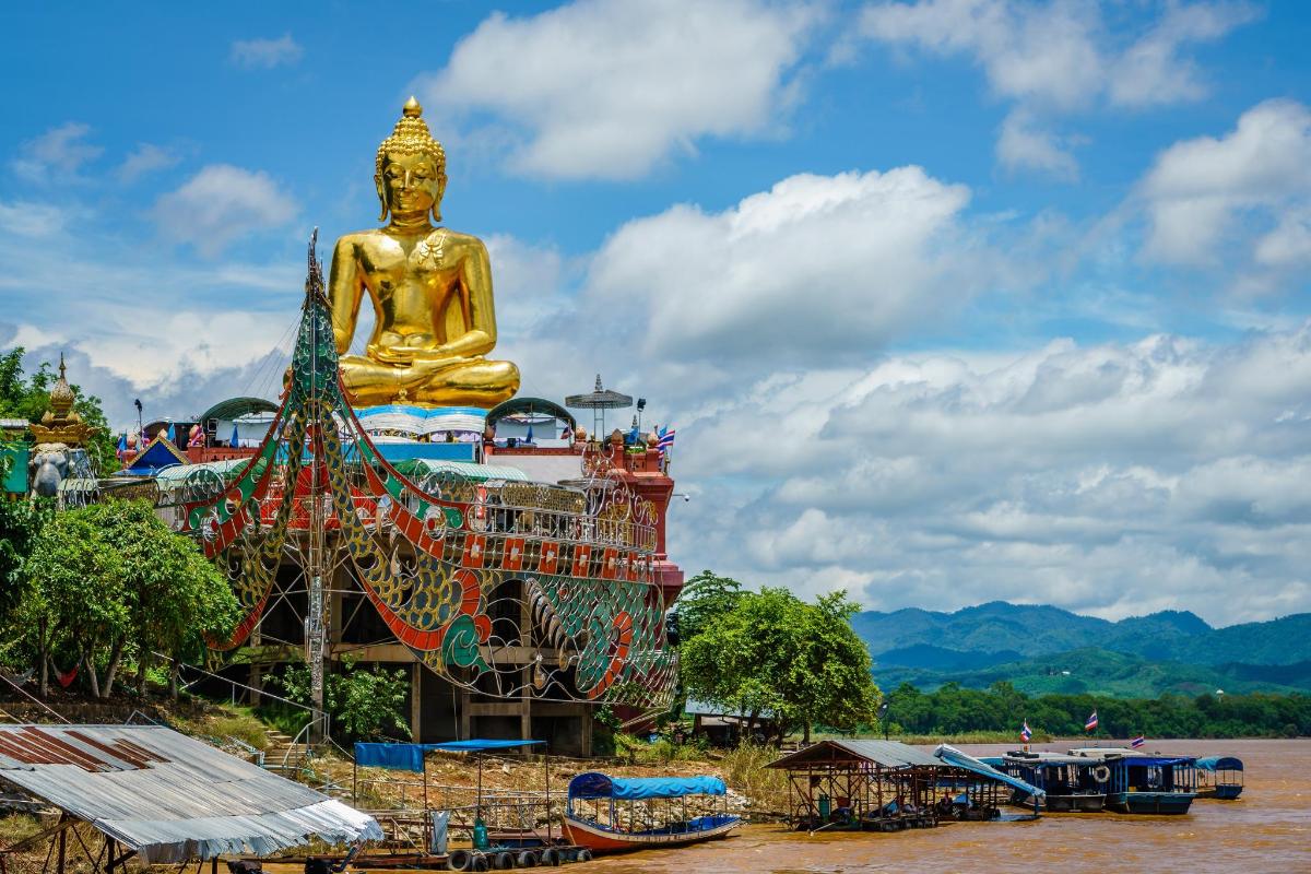 a large golden statue in the middle of a river