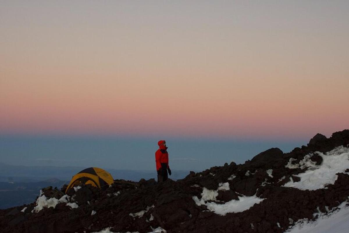 a person standing on top of a mountain with a tent