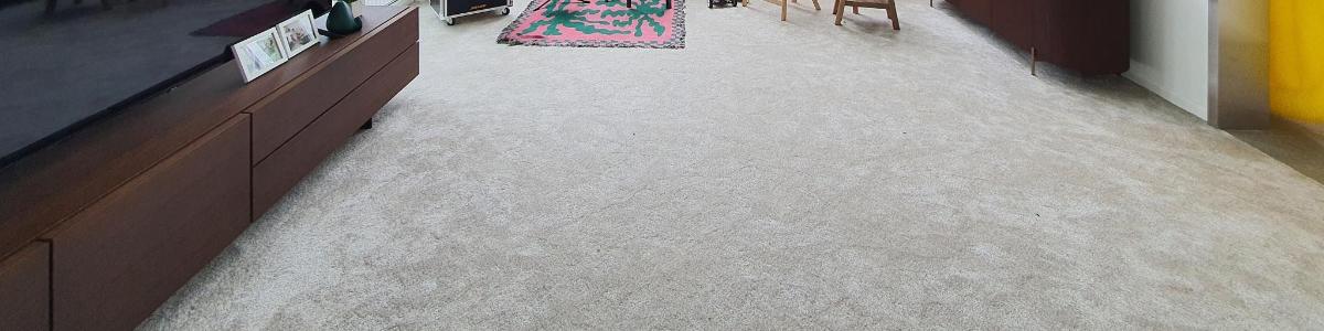 Una habitación con suelo alfombrado con una mesa y sillas.