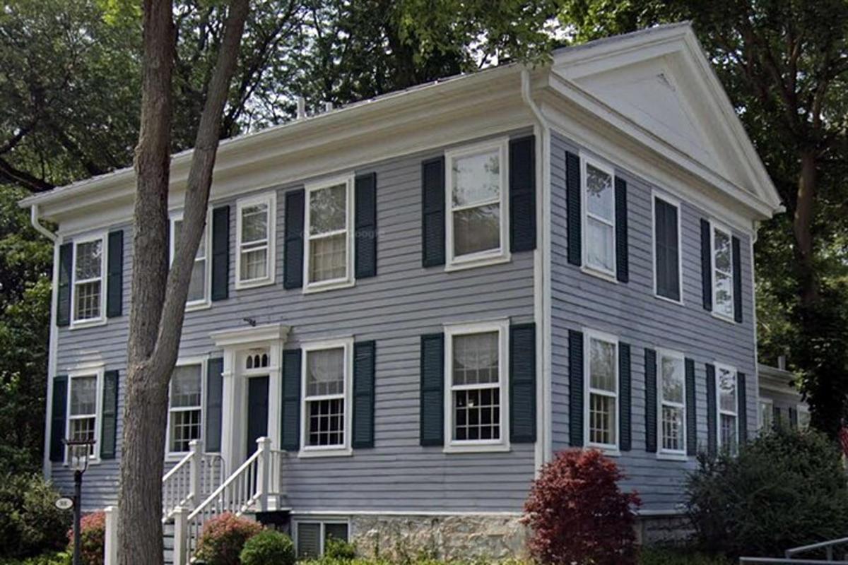 a gray house with black windows and a tree