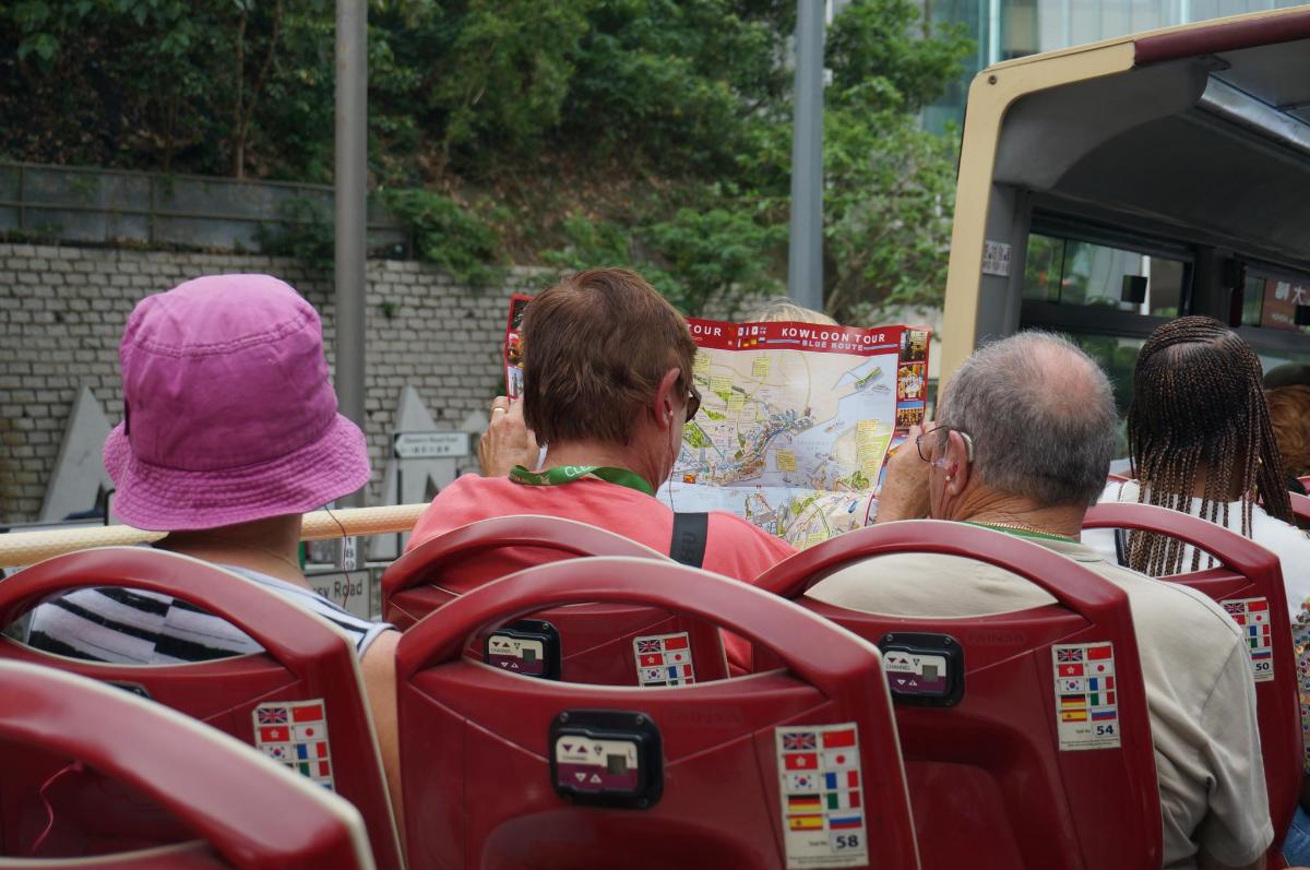 un grup de persones assegudes en un autobús mirant un mapa