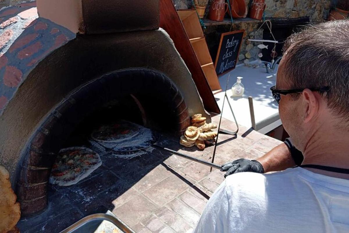 một người đàn ông đang cho thức ăn vào lò nướng pizza