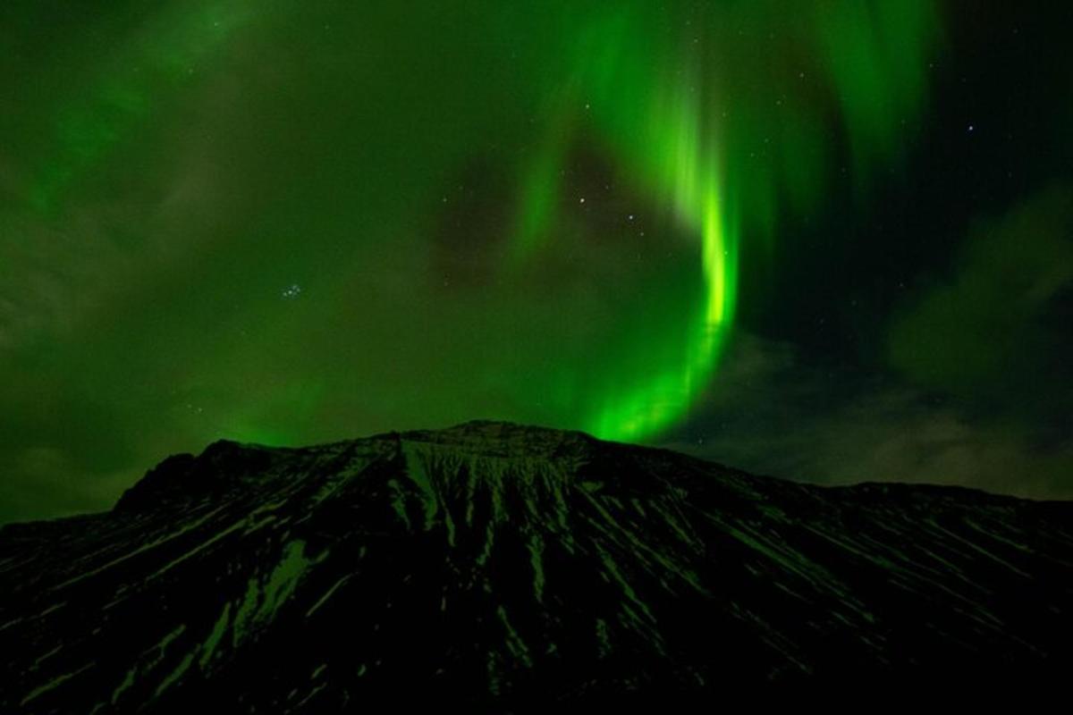 una imagen de la aurora bailando sobre una montaña