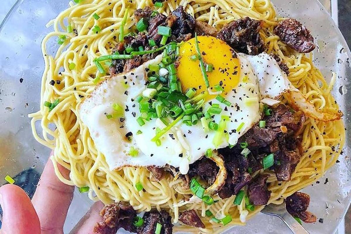 eine Person hält einen Teller Spaghetti mit Eiern darauf