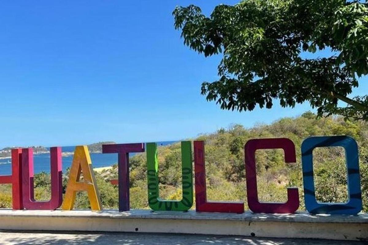 a sign for a beach with a tree in the background
