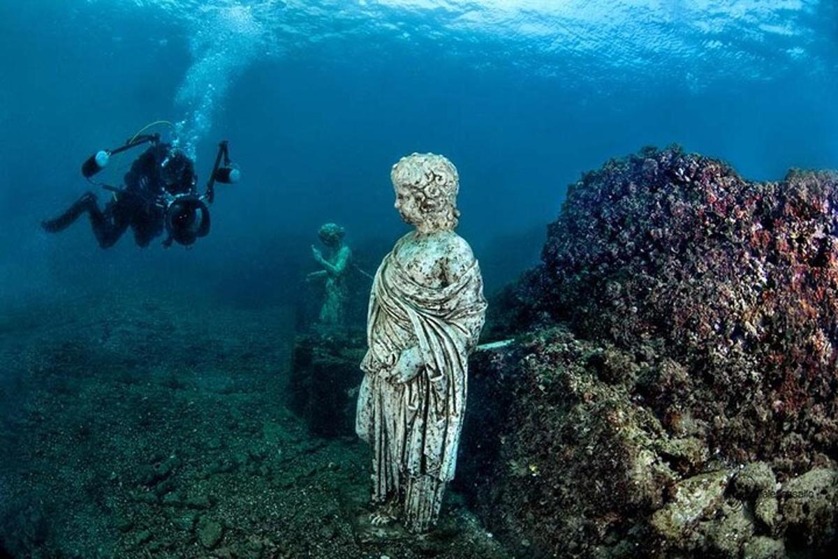 een persoon die een foto maakt van een standbeeld in de oceaan
