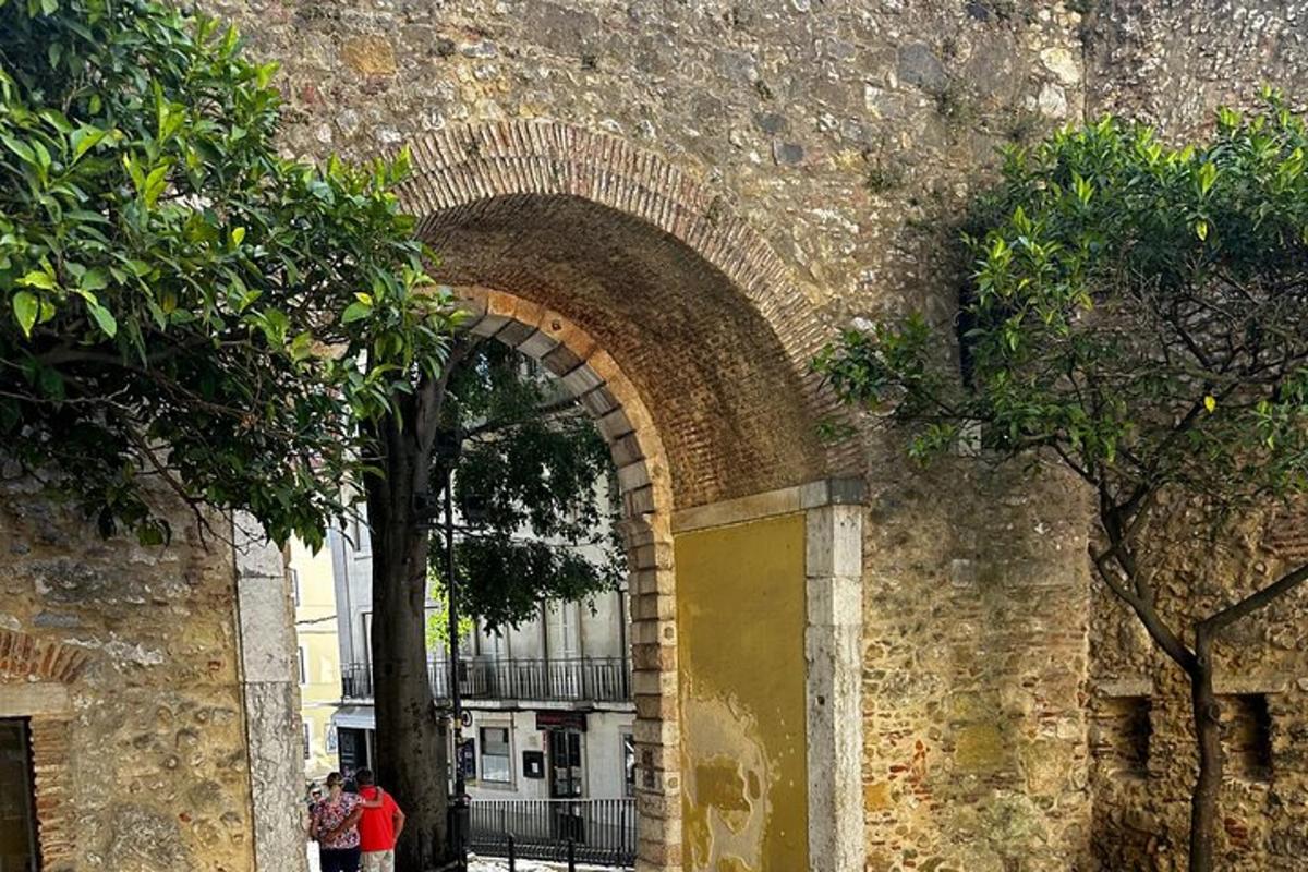 μια αψίδα σε έναν πέτρινο τοίχο με ανθρώπους να περπατούν μέσα από αυτήν