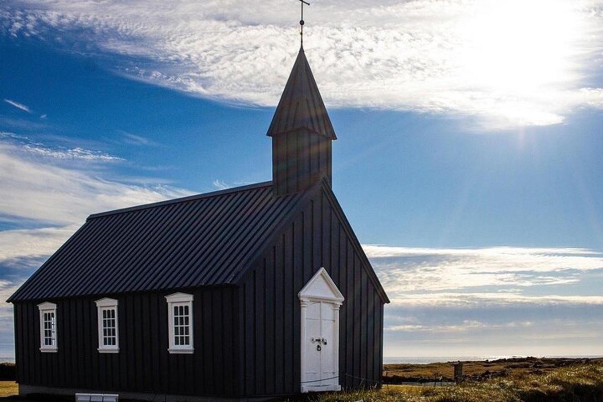 a black church with a steeple on a field
